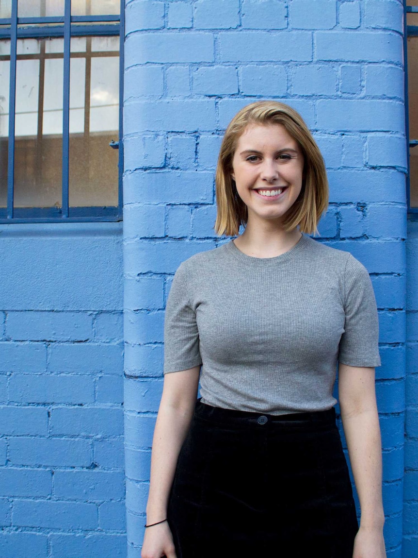 Morgan Koegel standing in front of a blue wall.