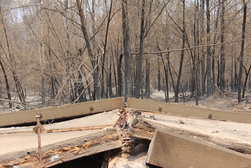 A bridge in a country area that has been destroyed by fire.