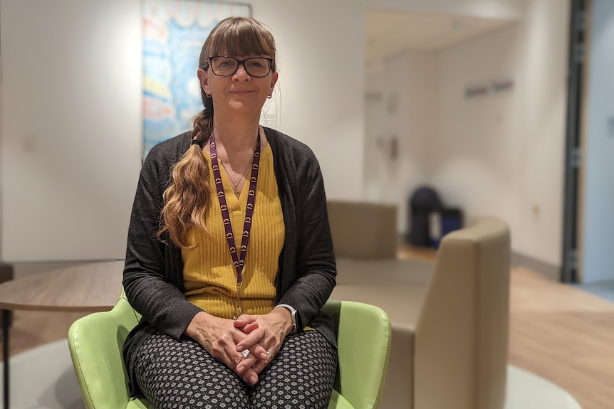 Ruth Lawrence sits on a green chair inside a consultation room at Midland Head to Health. 