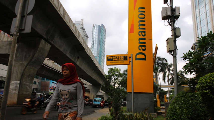 Woman walks in front of Bank Danamon headquarters in Jakarta