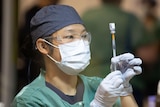 A nurse pulls up a syringe of COVID-19 vaccine.