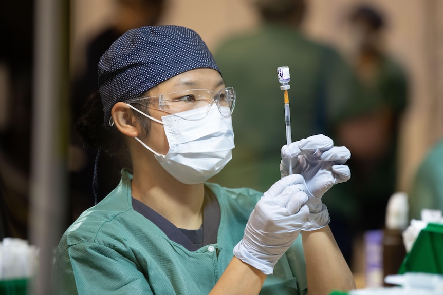 A nurse pulls up a syringe of COVID-19 vaccine.