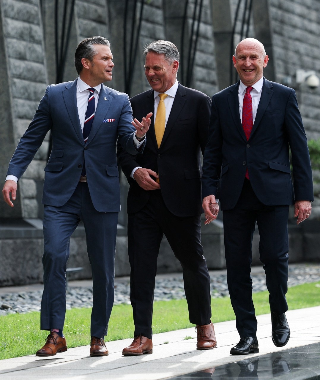 Three men in suits walking and laughing.