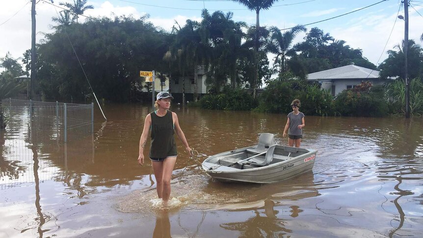 Innisfail resident Sharnie Morrissy drags a tinny through floodwaters in her street.