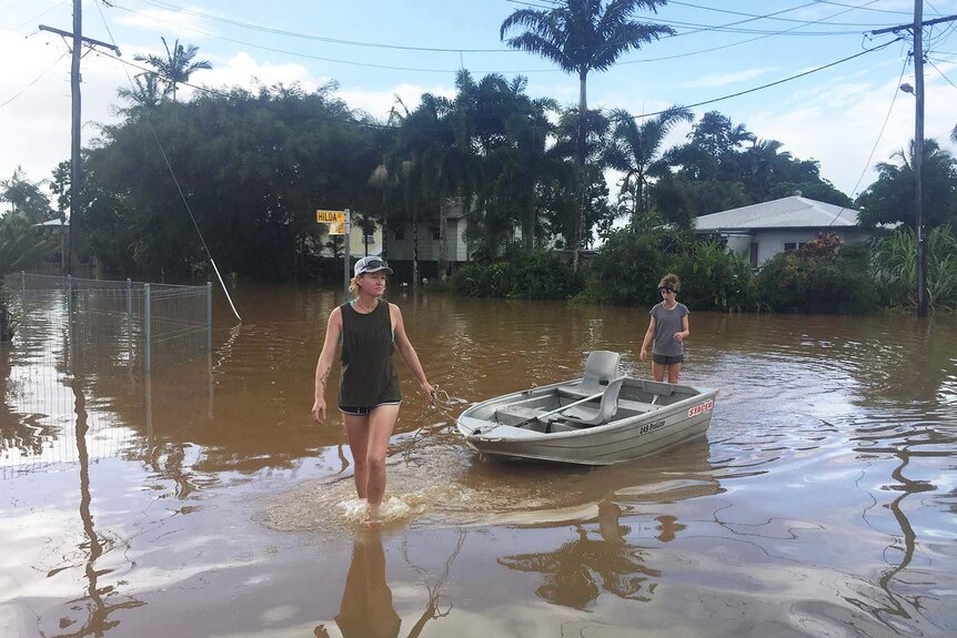 Innisfail resident Sharnie Morrissy drags a tinny through floodwaters in her street.