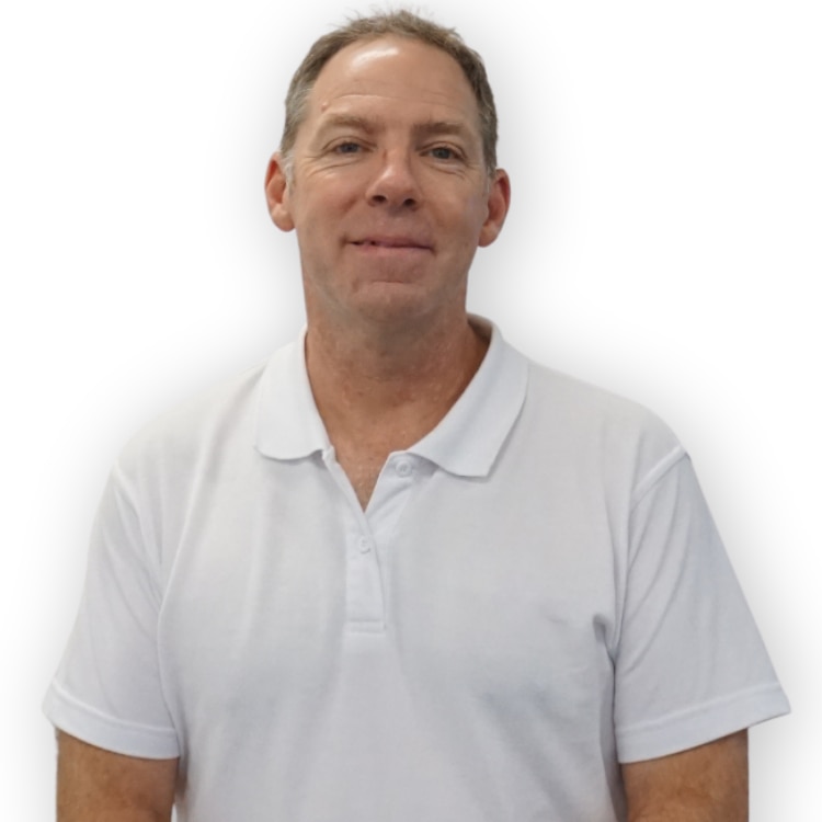 A man wearing a white top stands and smiles.