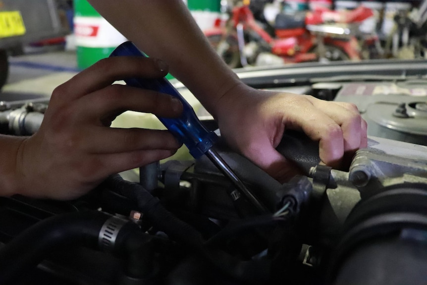 Close up of Madeline Moore's hands working on car