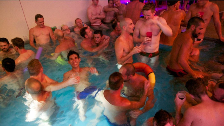 A group of gay men in their swimmers in a pool party