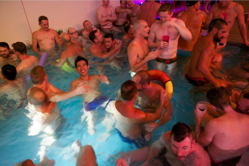 A group of gay men in their swimmers in a pool party