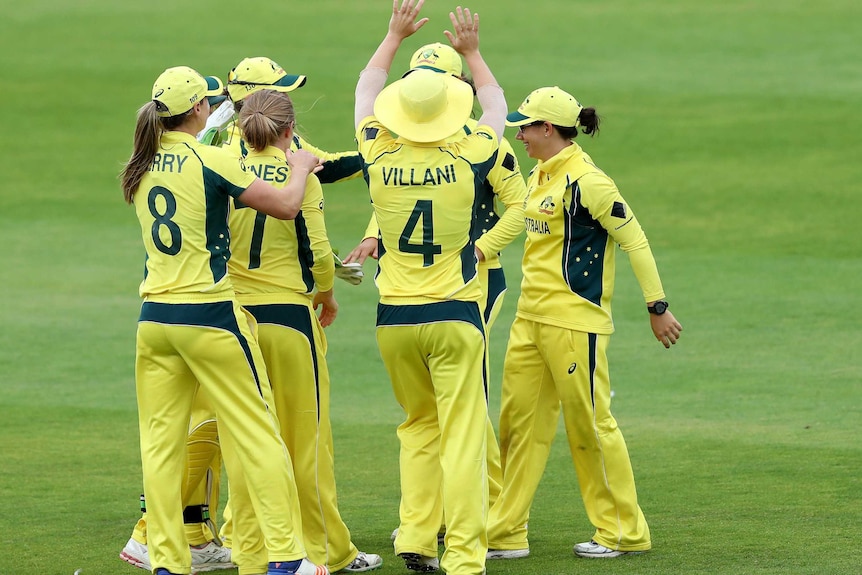 Australian players in a huddle celebrating a South African wicket.