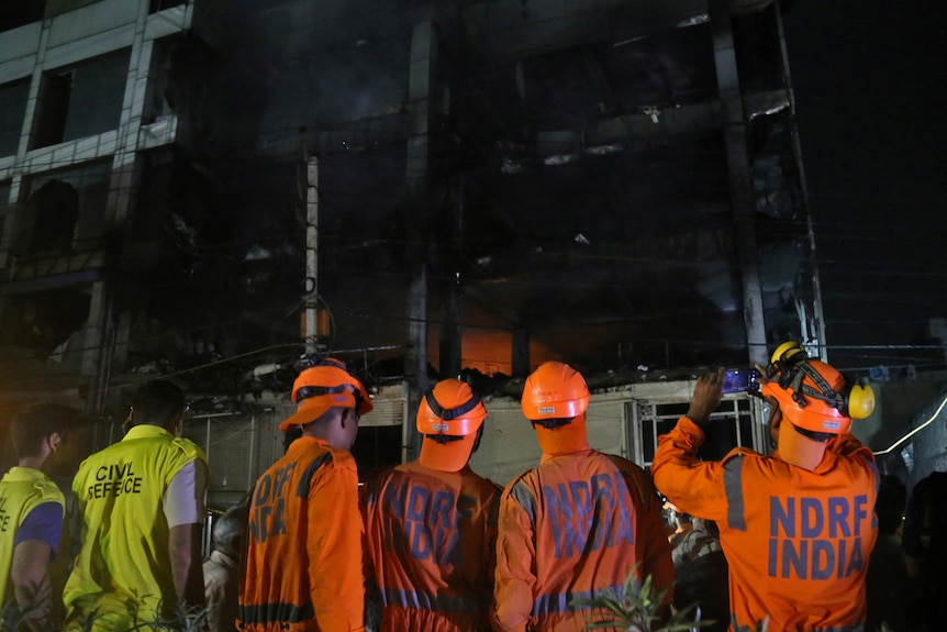 Authorities stand outside of burnt building.