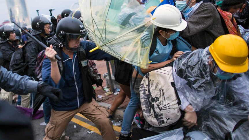 A police officer uses a baton on a pro-democracy protesters