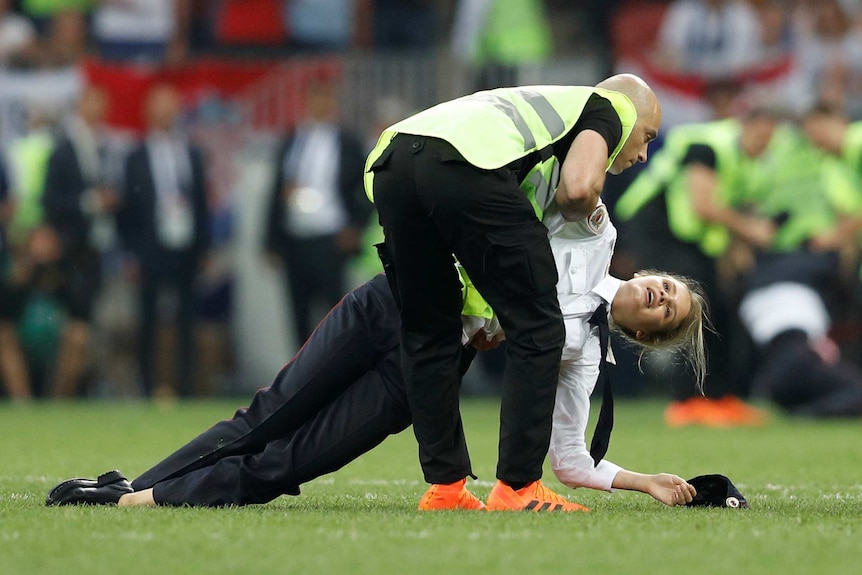 A steward apprehends a pitch invader