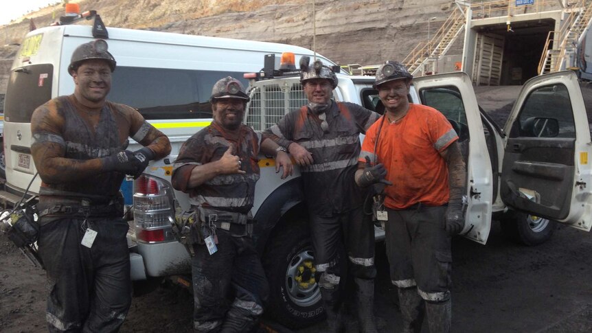 Four miners blackened with coal dust