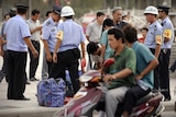 Ethnic Uighurs have their bags searched in the main square in Xinjiang's Kashgar city