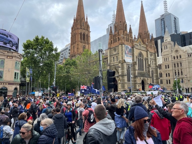 Une grande foule de personnes dans le CBD de Melbourne tenant des drapeaux. 