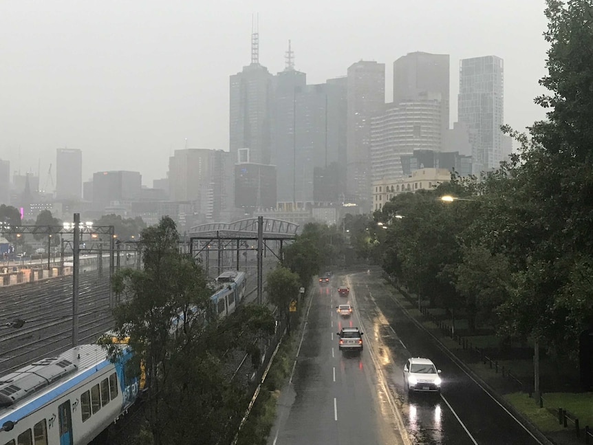 The Melbourne skyline shrouded in heavy rain near the rail line near the MCG.