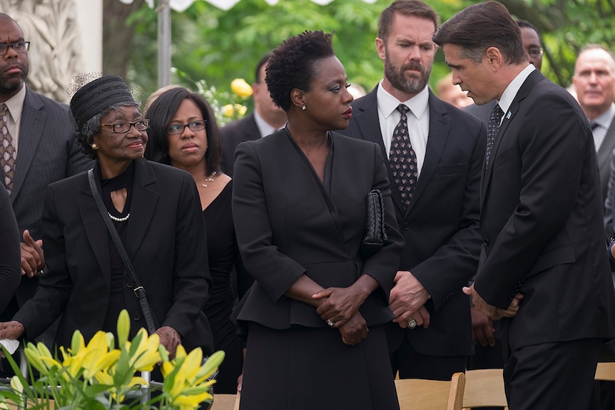 Colour still of Viola Davis and Colin Farrell conversing at a funeral in 2018 film Widows.