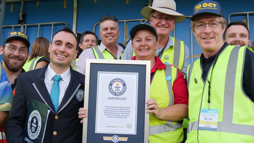 Men and women in high-vis jackets holding a world record certificate