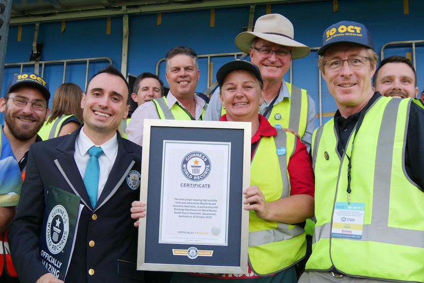 Men and women in high-vis jackets holding a world record certificate.