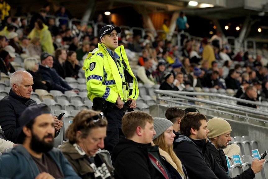 A policer officer looks on as he stands among the crowd at Perth Stadium during the AFL match against Geelong and Collingwood.