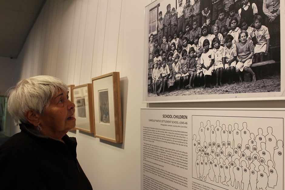 Alma studies a photo of herself as a young girl at the Carrolup Native Settlement School, circa 1945-46.