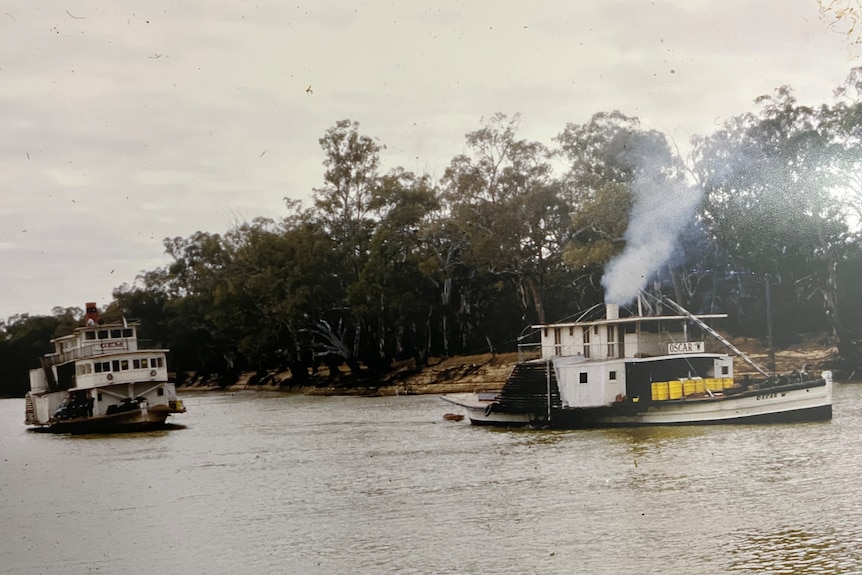 A paddle steamer towing a larger paddle steamer on the Murray River.