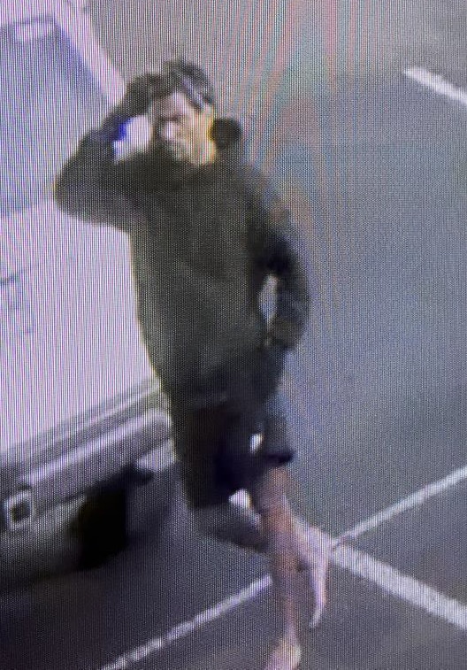 A grainy photo of a young man wearing gloves, a black hoody and sunglasses on perched on his head.