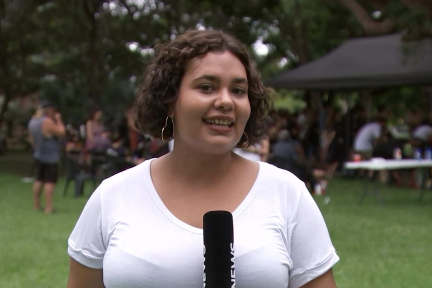 Woman holding microphone standing in front of a crowd.