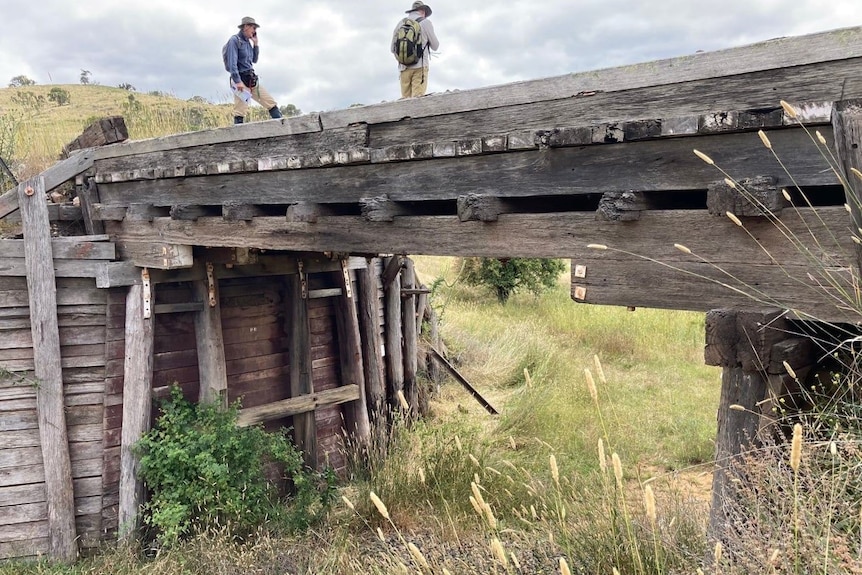 Two men stand on an old wooden railway bridge