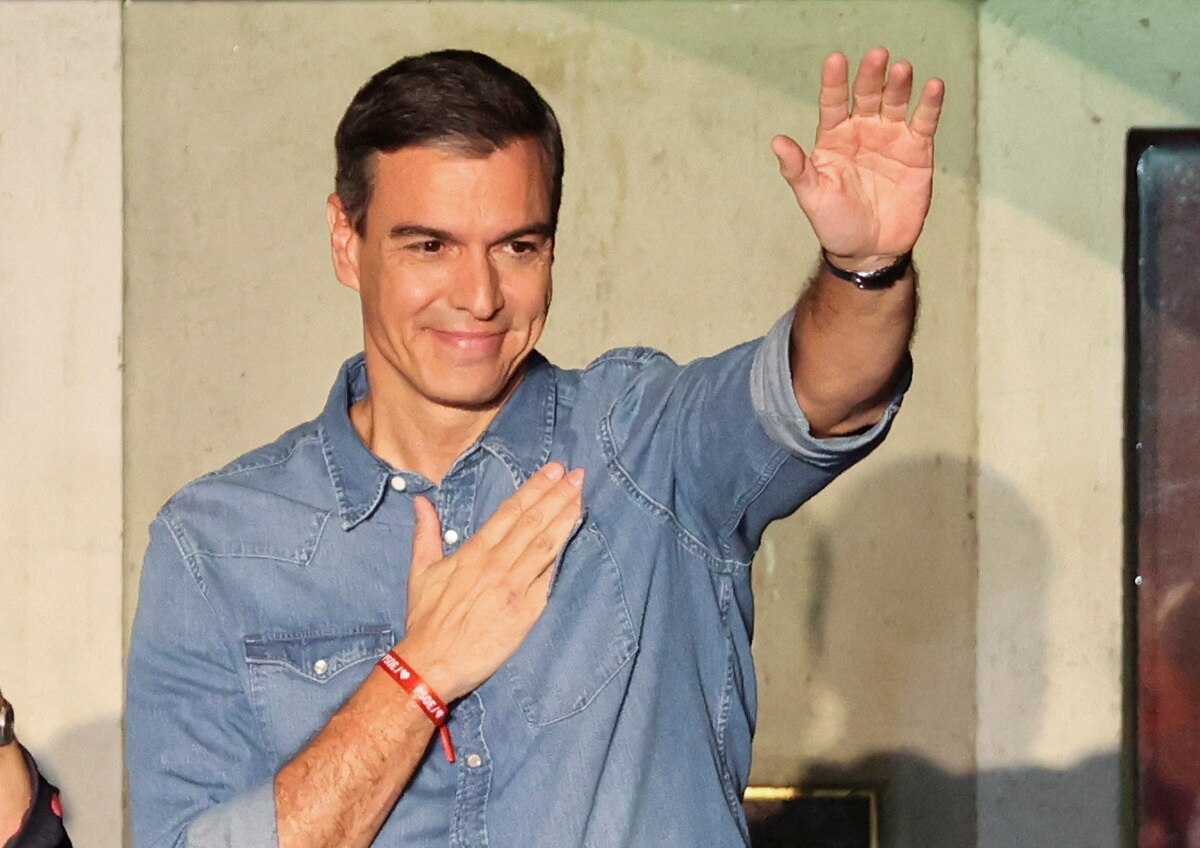 Pedro Sanchez puts his right hand over his heart and waves with his left hand.