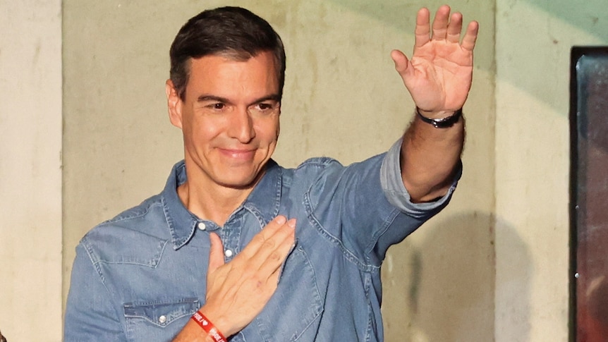 Pedro Sanchez puts his right hand over his heart and waves with his left hand.