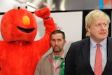A person dressed as Elmo next to Boris Johnson next to a person dressed as a bin