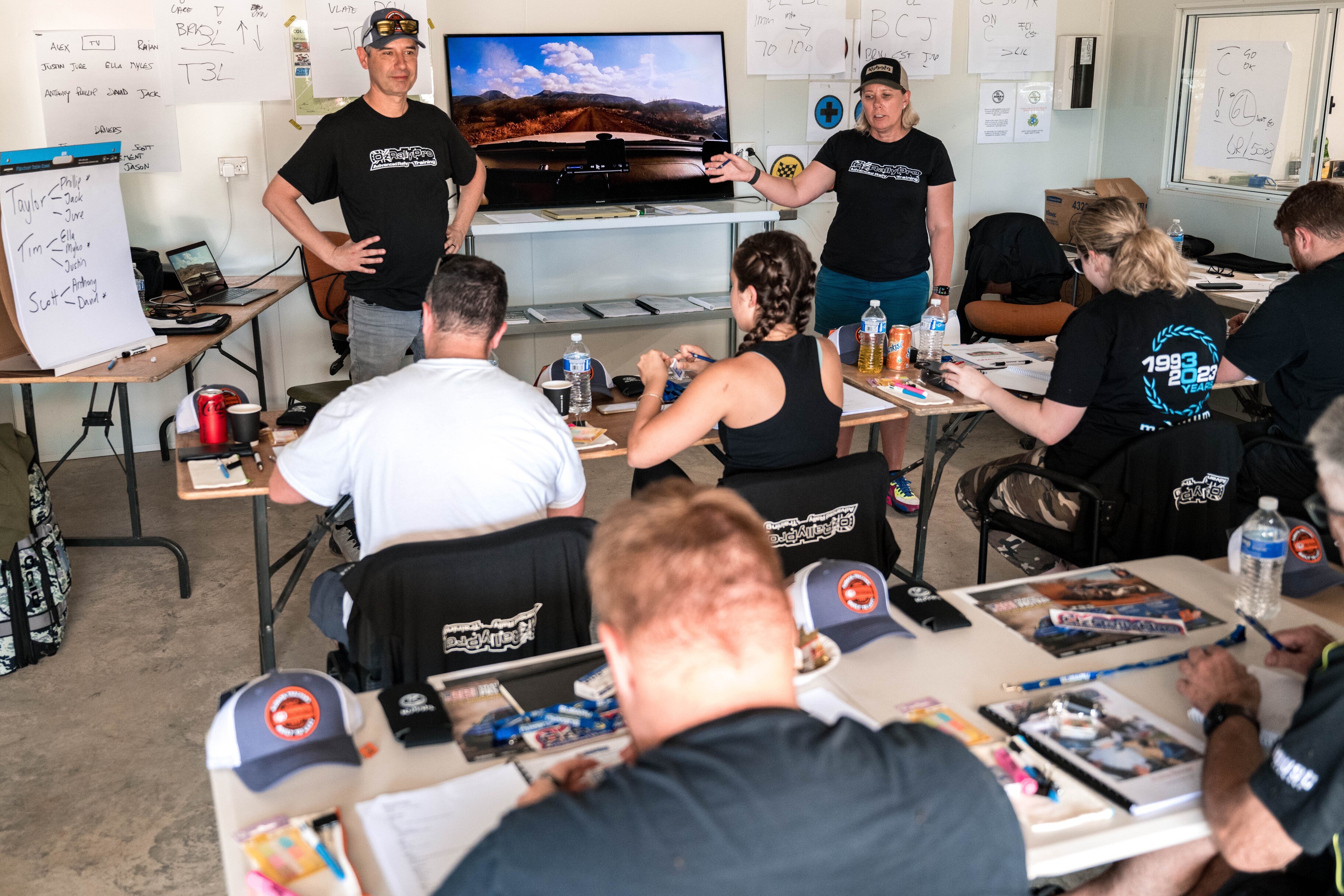 Muškarac i žena koji stoje ispred malog razreda učenika.