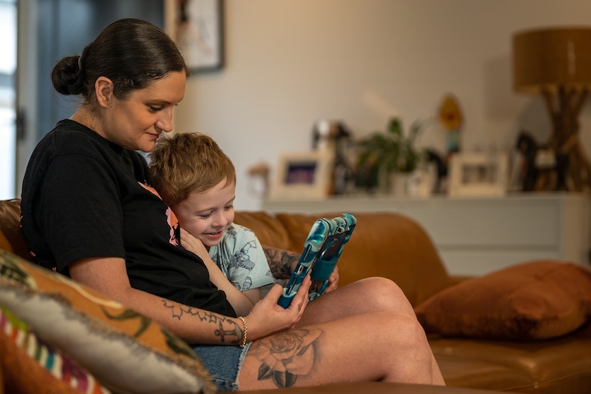 Kiara Neil and child sitting on a couch watching an tablet