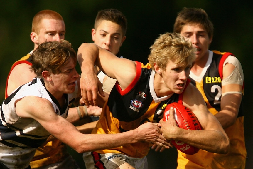 A young footballer attempts to break a tackle