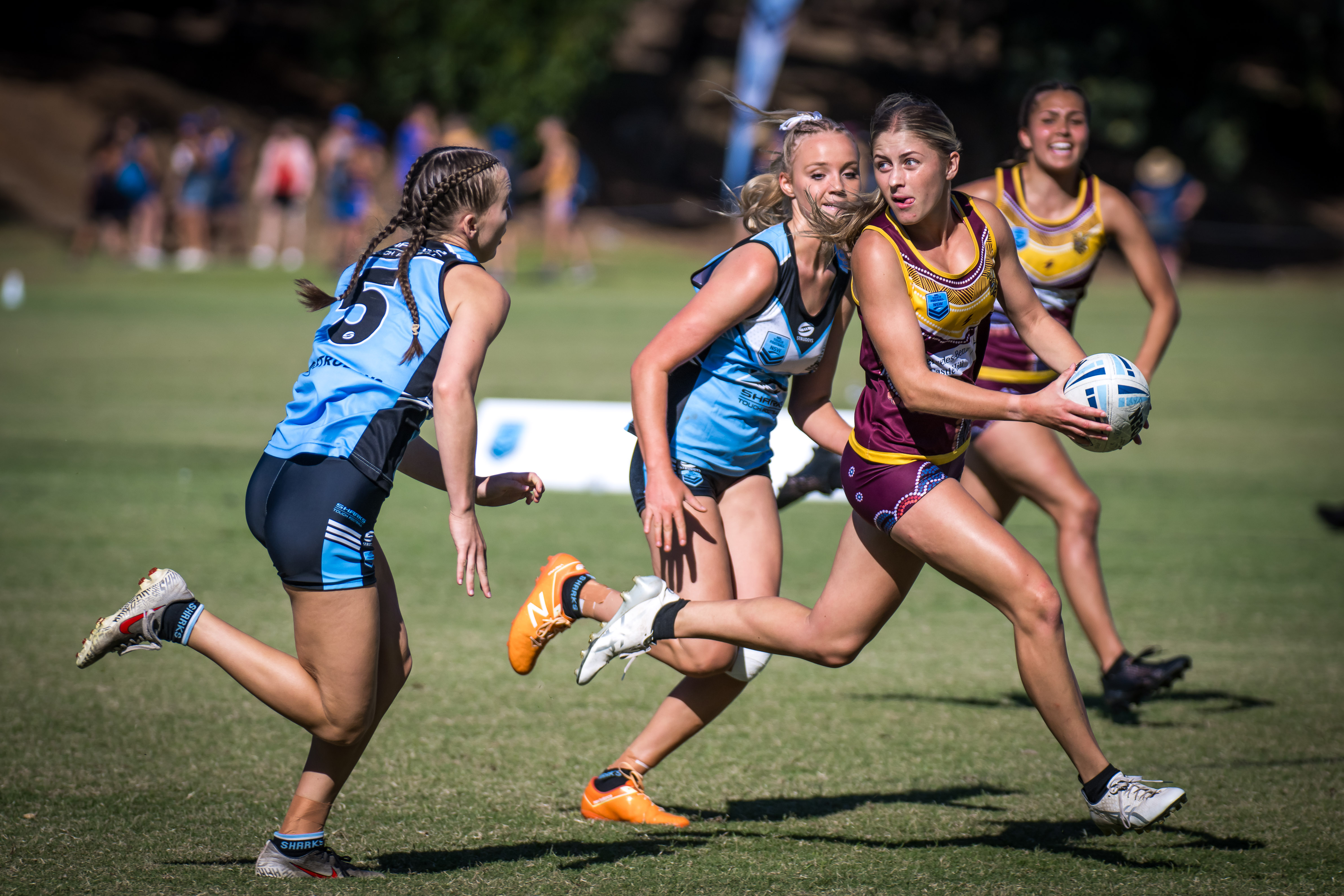 teenage girls play touch football, one in a maroon outfit prepares to throw the ball.