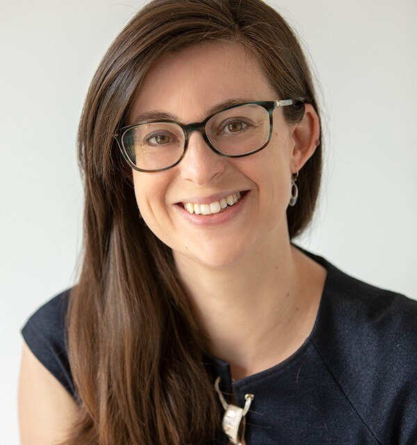 A woman with brown hair and glasses smiles at the camera
