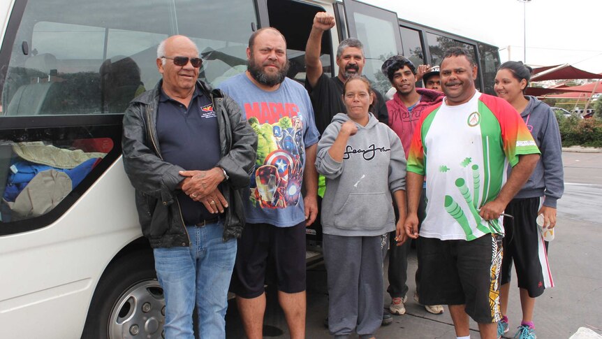 Eight Indigenous locals from Wilcannia stand in front of a bus