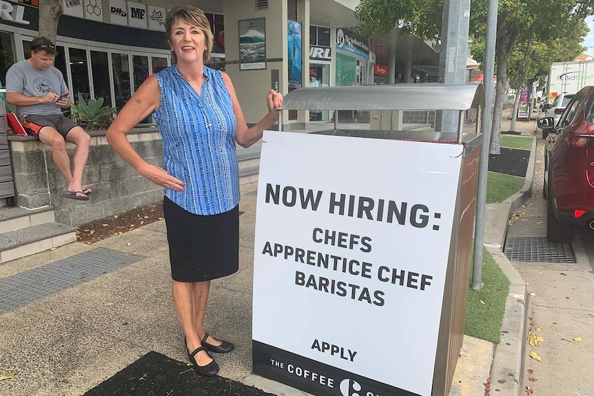 Coffee Club shop owner Julie-Anne Lean stands next to a sign advertising available jobs at her Gold Coast business.