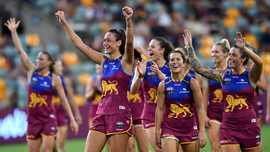 Brisbane Lions AFLW players smile and wave to fans at the Gabba.