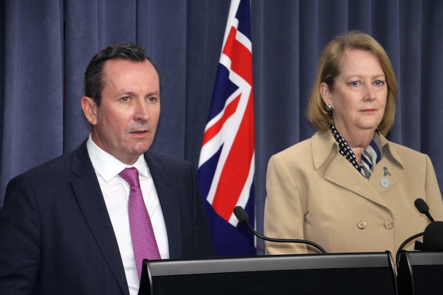 Mark McGowan and Michelle Roberts in front of a flag.