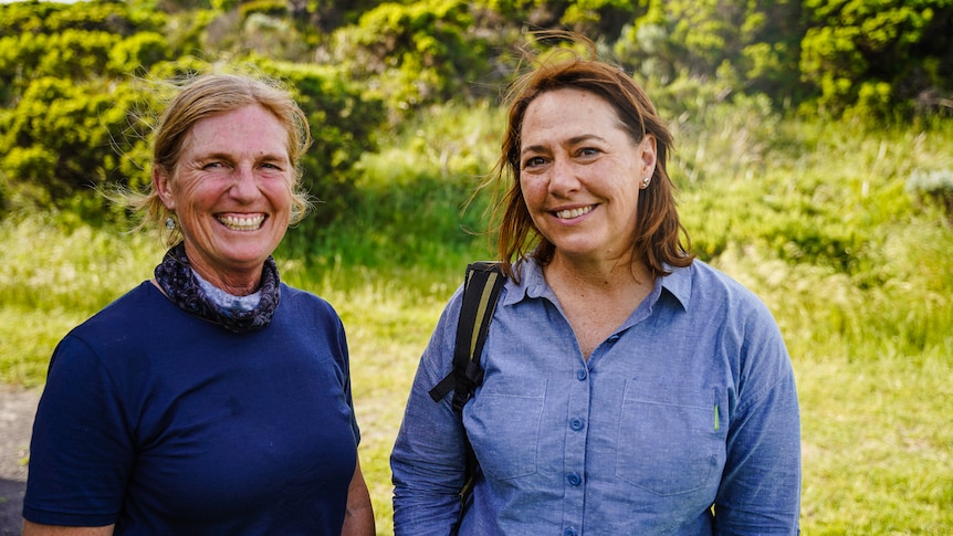 Two women stand smiling next to each other.