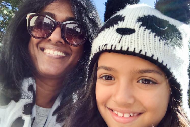 Throshni Naidoo and her young daughter, who is wearing a panda beanie, smile in a selfie photo.