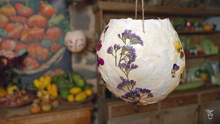 A spherical papermache light covered in dried flowers.