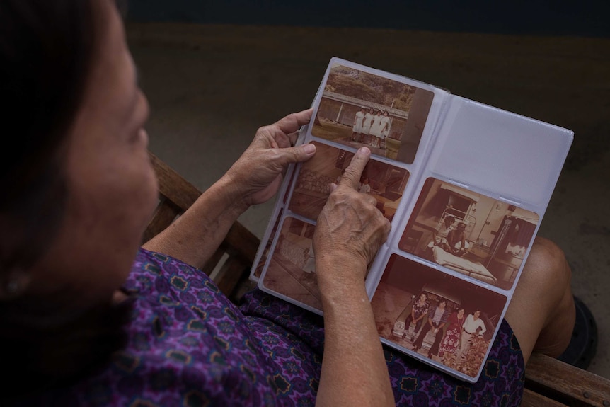 Doreen Soh, a former midwife on Christmas Island, looks through old photos at her apartment.