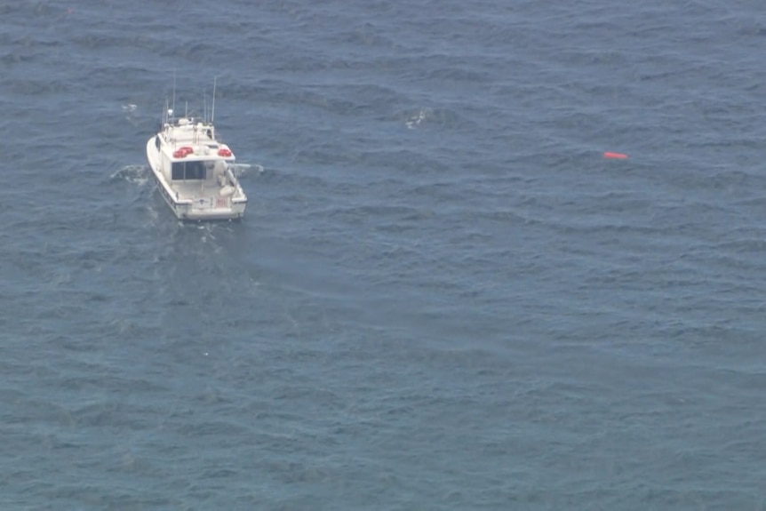 An aerial view of a boat near a small piece of what appears to be floating debris.