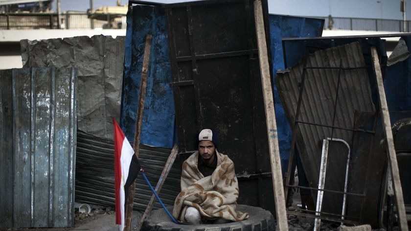 An anti-government protester sits in a tyre at a barricade near Tahrir Square in Cairo on February 6, 2011.