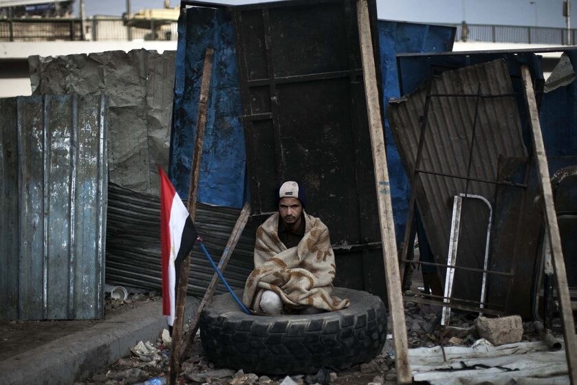 An anti-government protester sits in a tyre at a barricade near Tahrir Square in Cairo on February 6, 2011.