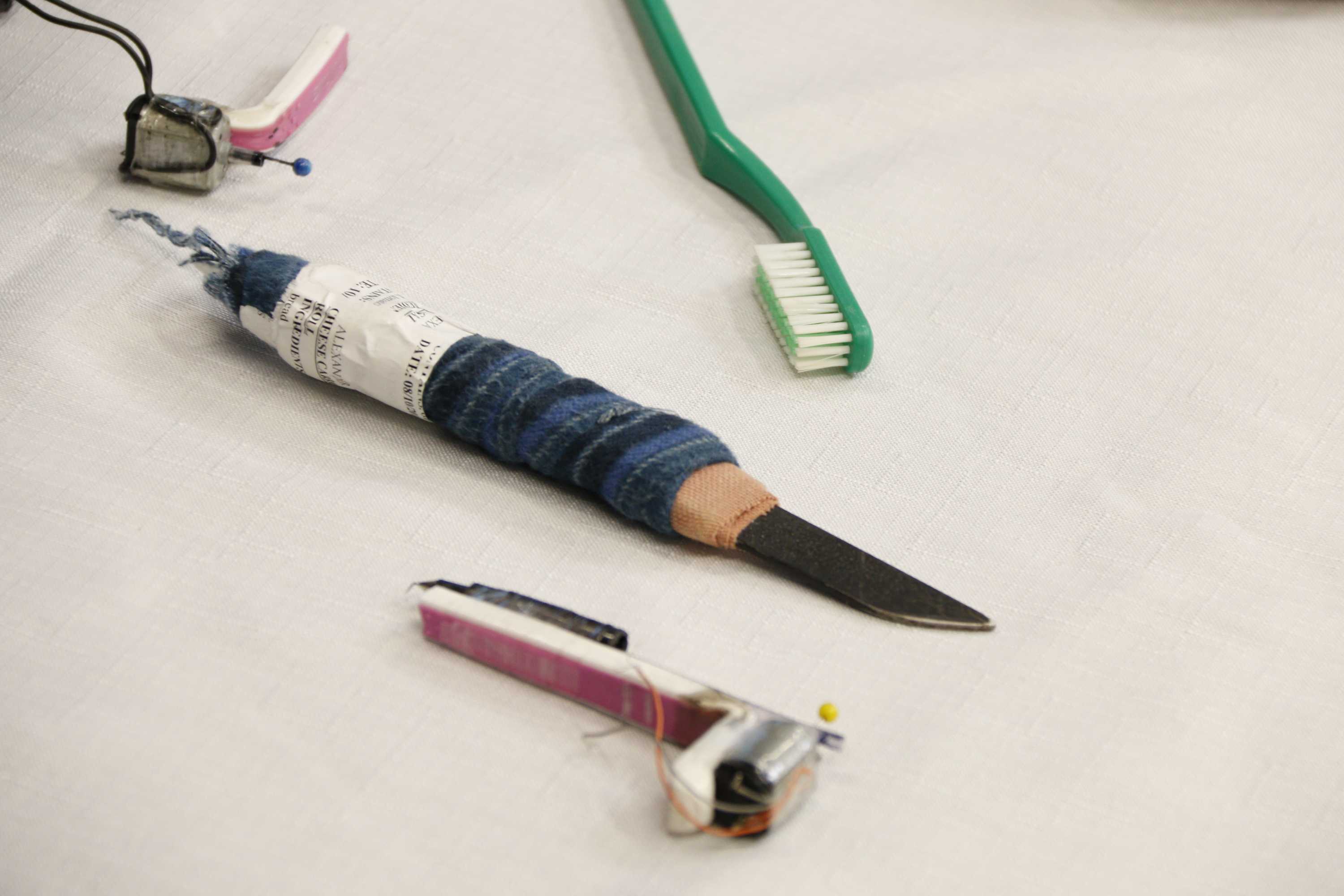 An improvised knife made of metal, cloth and tape lies on a table.